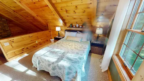 Loft queen bed beside a sunny window