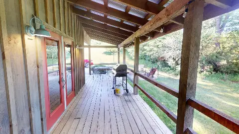 Covered back deck with red doors, grill and patio table