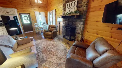 Living room with sofa and recliners facing the stone fireplace