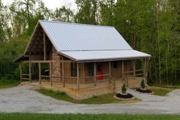 log cabin with wrap around porch and metal roof