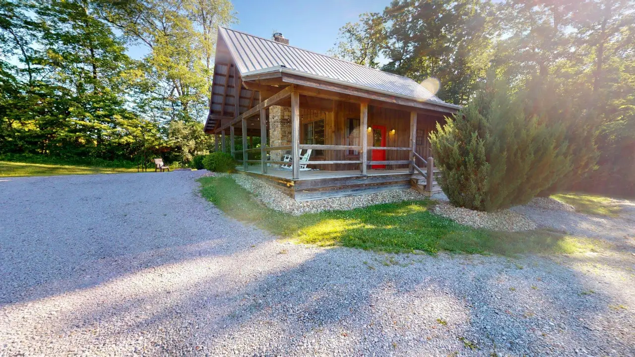 Twin Pine Cottage with metal roof, covered porch and gravel drive in the trees